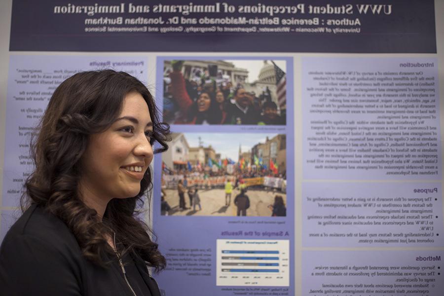 Una estudiante frente a su póster de investigación de pregrado.