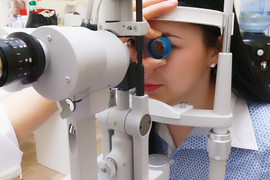 A person gets their eyes checked with an ophthalmoscope.