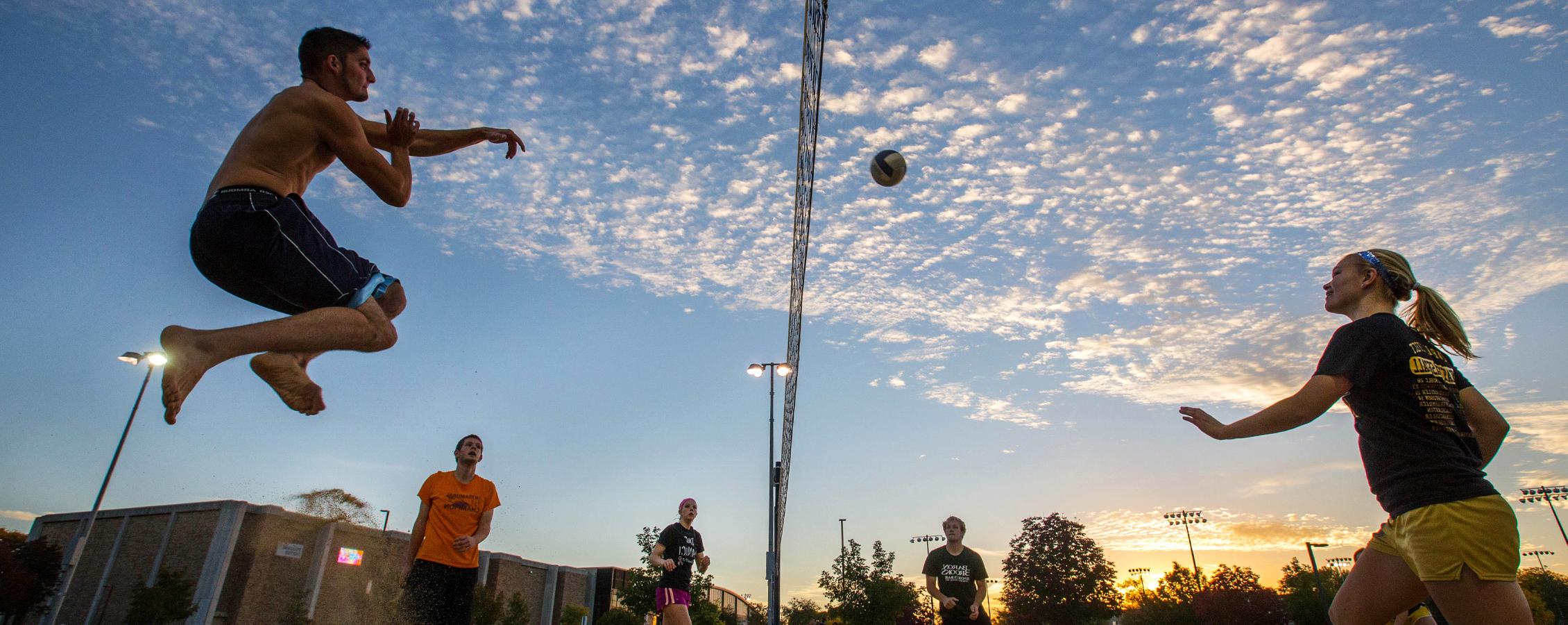 Two people on opposite sides of a volleyball net hit the ball back and forth.