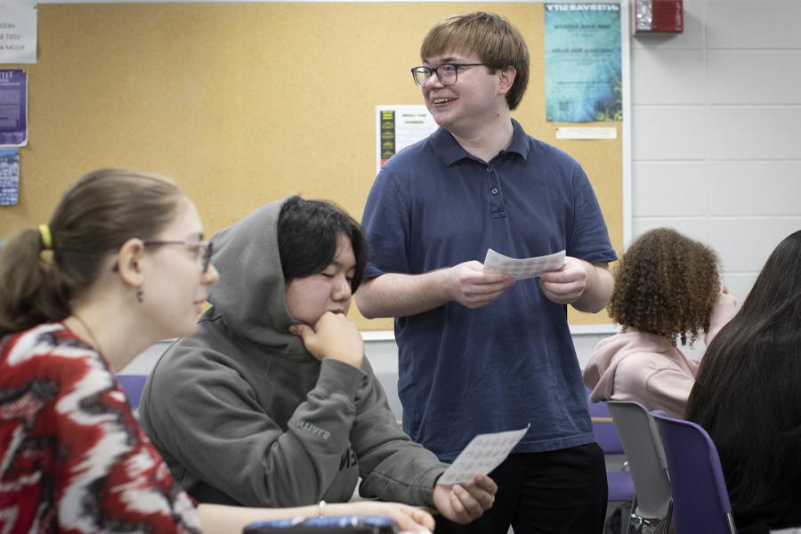 A student stands and smiles in a classroom.